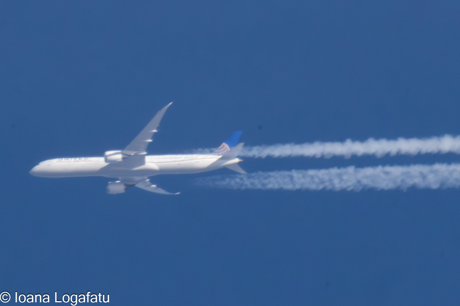 Cloud trails mark the sky as an airplane glides by